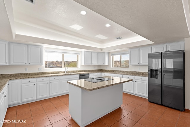 kitchen featuring light tile patterned flooring, a raised ceiling, a kitchen island, and appliances with stainless steel finishes