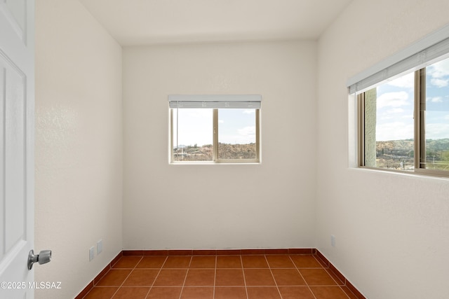 empty room with dark tile patterned flooring and plenty of natural light