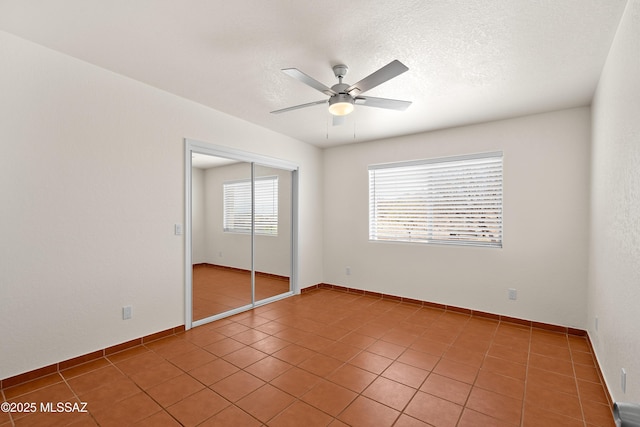 unfurnished bedroom featuring a closet, a textured ceiling, a ceiling fan, and light tile patterned floors