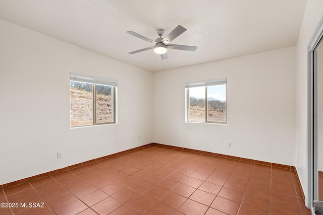 empty room featuring tile patterned floors, baseboards, and a ceiling fan