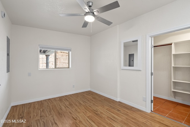unfurnished bedroom featuring electric panel, baseboards, and light wood finished floors