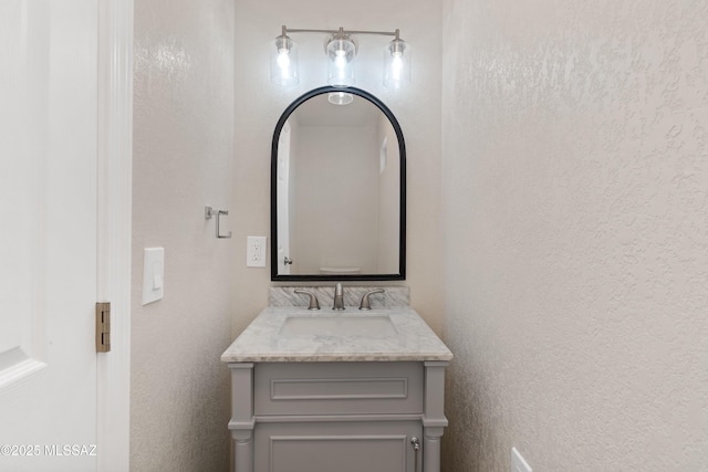 bathroom with a textured wall and vanity