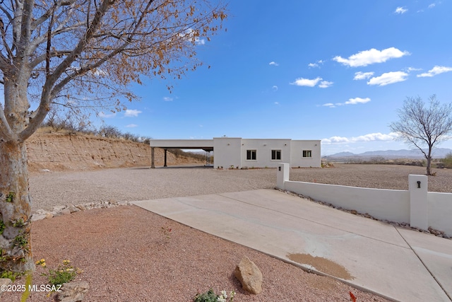 view of front of property with driveway, fence, an attached carport, stucco siding, and a mountain view