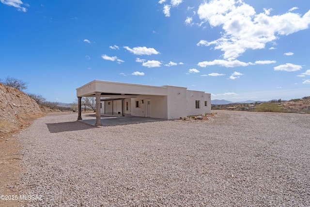 rear view of property with an attached carport, stucco siding, and a patio area