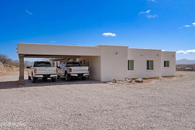 view of front of property with gravel driveway, a carport, and stucco siding