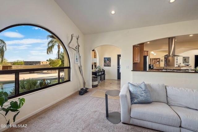 living room featuring recessed lighting, arched walkways, baseboards, and light carpet