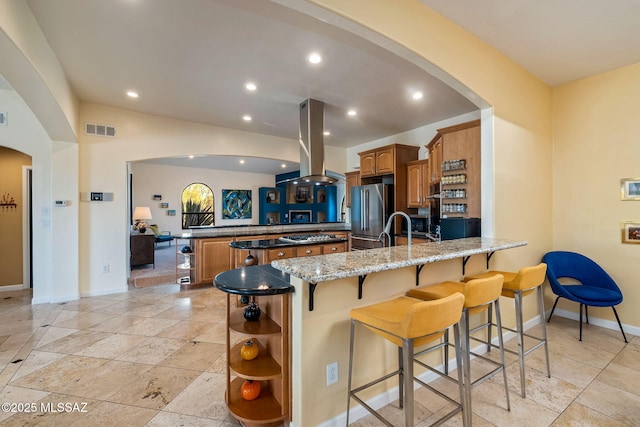 kitchen featuring brown cabinets, a peninsula, baseboards, and island range hood