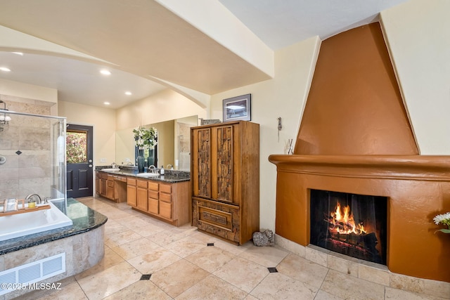 bathroom with a bath, a fireplace, a shower stall, a sink, and recessed lighting