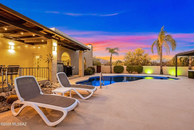 pool at dusk featuring a patio, a fenced backyard, and a fenced in pool
