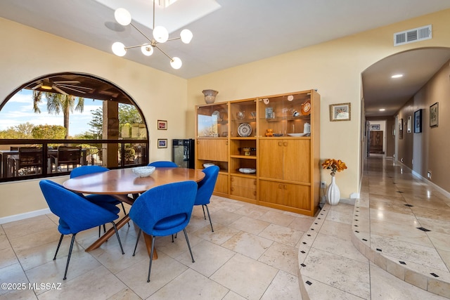 dining space with arched walkways, baseboards, visible vents, and a chandelier