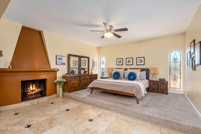 carpeted bedroom featuring a ceiling fan, baseboards, and a fireplace