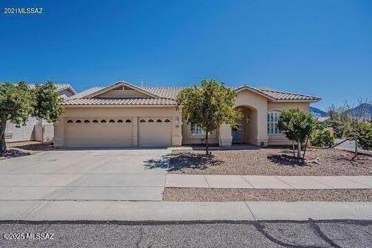 view of front of home with a tile roof, driveway, stucco siding, and an attached garage