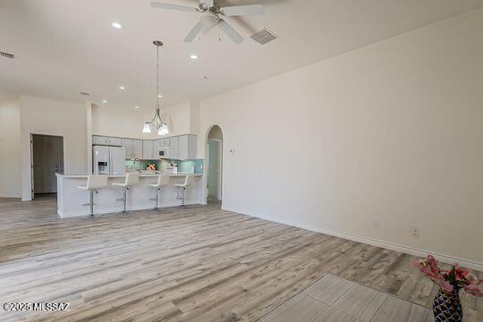 kitchen with white fridge with ice dispenser, open floor plan, visible vents, arched walkways, and ceiling fan