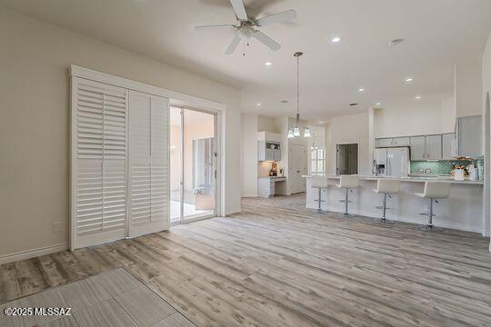 kitchen featuring light countertops, light wood-type flooring, gray cabinets, white refrigerator with ice dispenser, and ceiling fan