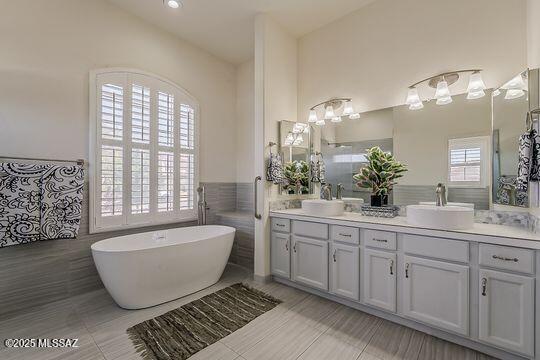 full bathroom featuring plenty of natural light, double vanity, and a sink