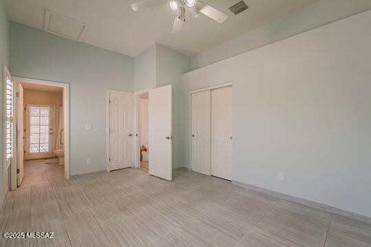 unfurnished bedroom featuring a closet, a ceiling fan, visible vents, and attic access