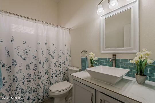 bathroom featuring a shower with curtain, toilet, vanity, and tasteful backsplash