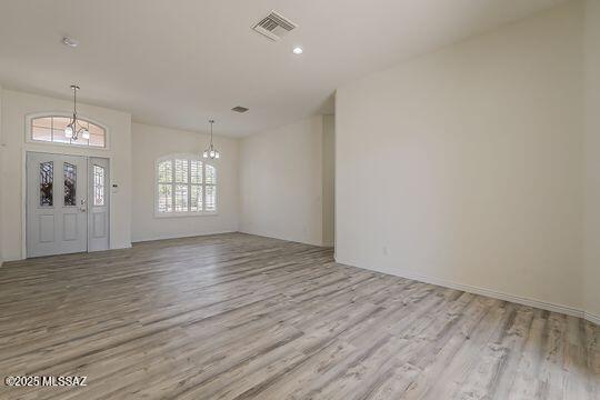 foyer featuring wood finished floors, a notable chandelier, and visible vents