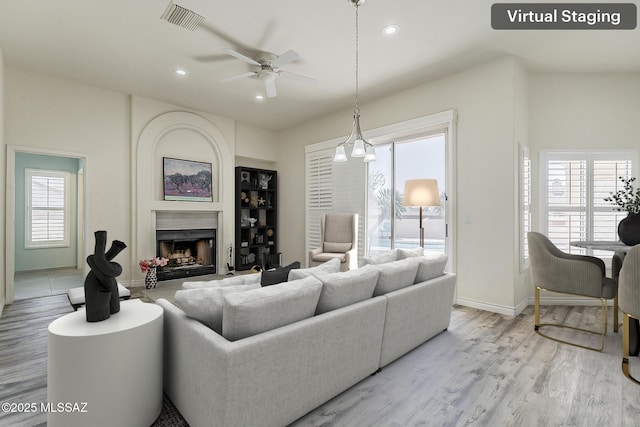 living room featuring light wood finished floors, a premium fireplace, visible vents, ceiling fan, and recessed lighting