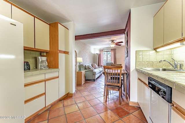 kitchen with a sink, freestanding refrigerator, tile counters, stainless steel dishwasher, and light tile patterned floors