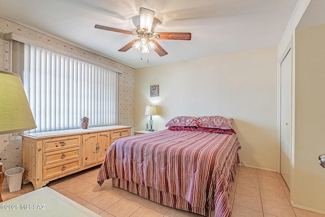 bedroom featuring light tile patterned flooring, wallpapered walls, a closet, and a ceiling fan