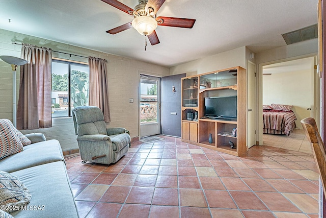 living area featuring tile patterned flooring, visible vents, and ceiling fan