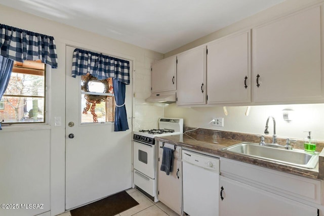 kitchen with white appliances, white cabinetry, dark countertops, under cabinet range hood, and a sink