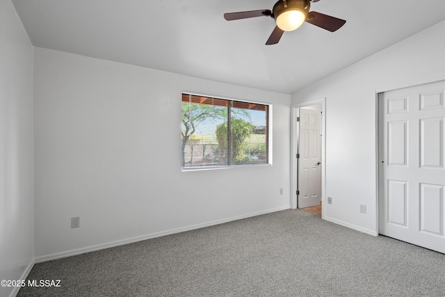 unfurnished bedroom featuring a ceiling fan, carpet floors, lofted ceiling, and baseboards