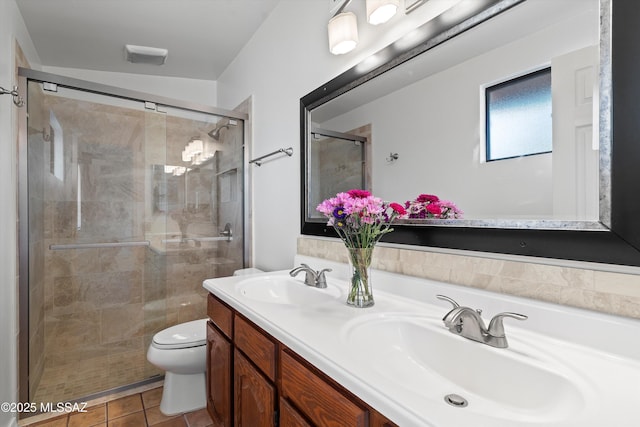 bathroom featuring double vanity, toilet, a stall shower, and a sink