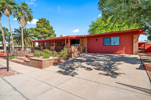single story home with stone siding, concrete driveway, and fence