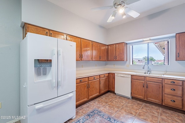 kitchen featuring light countertops, a sink, brown cabinetry, and white appliances