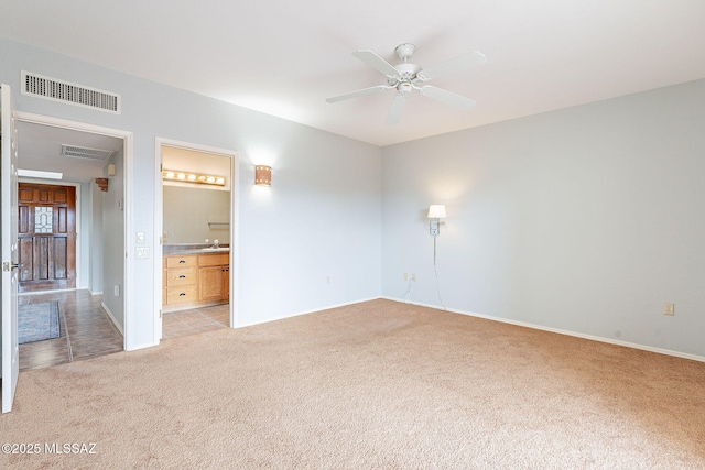 unfurnished bedroom featuring a sink, connected bathroom, visible vents, and light colored carpet