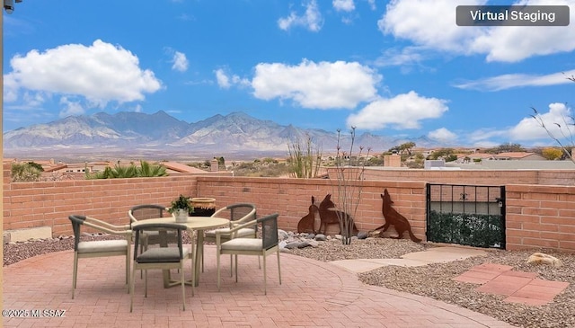 view of patio / terrace featuring outdoor dining space, fence, and a mountain view