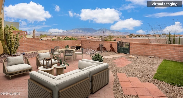 view of patio featuring outdoor lounge area, a mountain view, outdoor dining area, and a fenced backyard