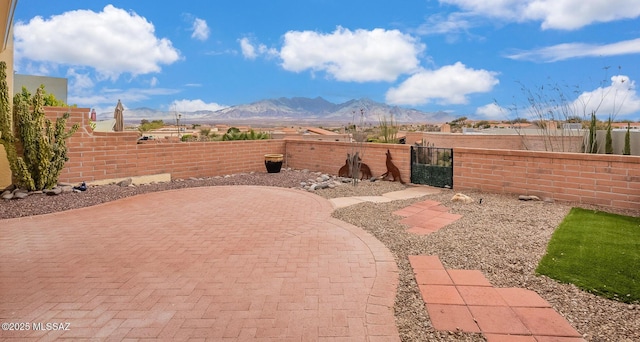 view of yard featuring a patio, a gate, a mountain view, and a fenced front yard