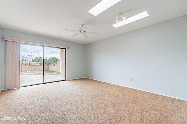 empty room featuring baseboards, ceiling fan, lofted ceiling with skylight, and carpet