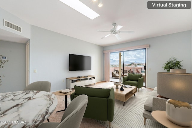 living room with baseboards, a ceiling fan, visible vents, and a skylight
