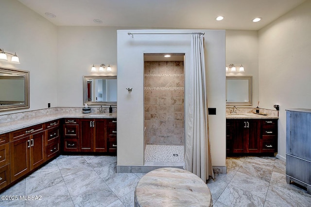 bathroom with recessed lighting, two vanities, tiled shower, and a sink