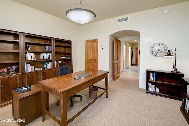 office space with arched walkways, baseboards, visible vents, and light colored carpet