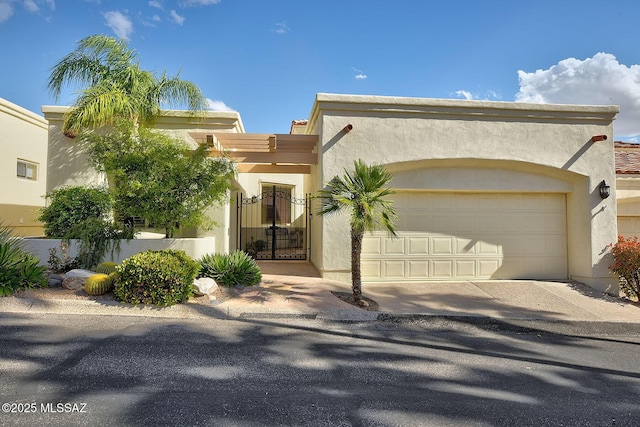 pueblo-style house featuring a garage, driveway, and stucco siding