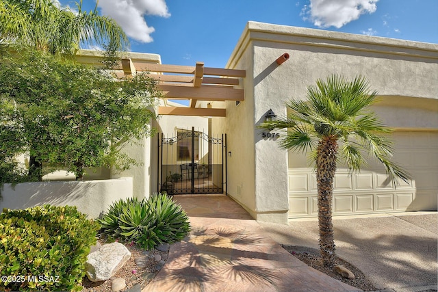 property entrance featuring a garage, stucco siding, and a gate
