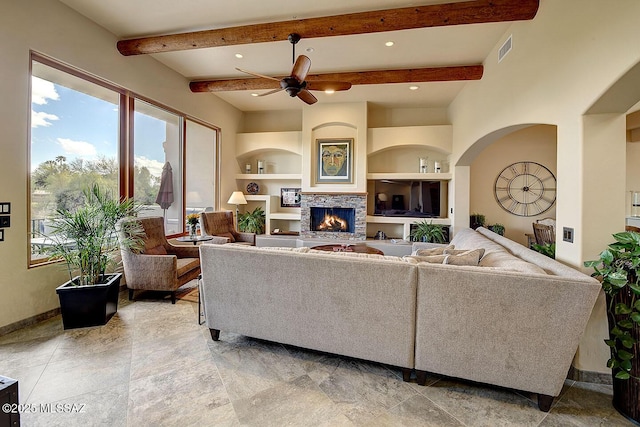 living room featuring beam ceiling, baseboards, built in features, a ceiling fan, and a lit fireplace