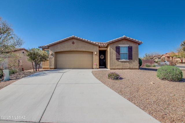 view of front of home featuring an attached garage, a tile roof, driveway, and stucco siding