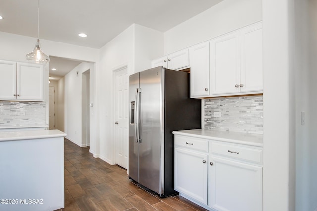 kitchen featuring white cabinets, decorative backsplash, pendant lighting, stainless steel refrigerator with ice dispenser, and light countertops