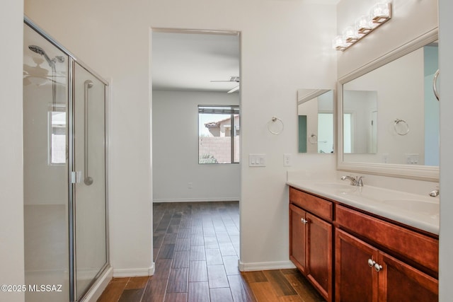 bathroom featuring double vanity, a stall shower, and a sink