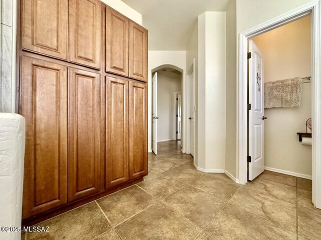 hallway with arched walkways and baseboards