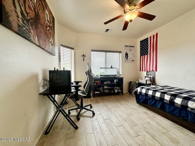 bedroom with wood finished floors, ceiling fan, and visible vents