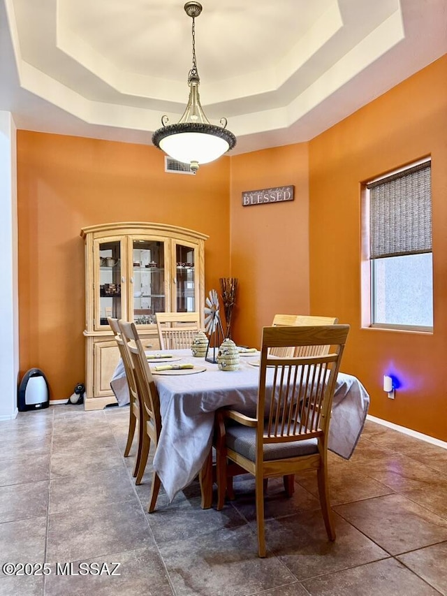 dining area featuring a tray ceiling, baseboards, and visible vents