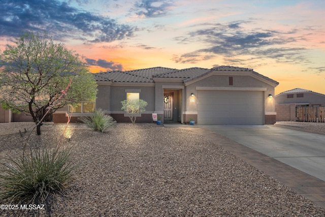 view of front of house featuring an attached garage, a tile roof, concrete driveway, and stucco siding