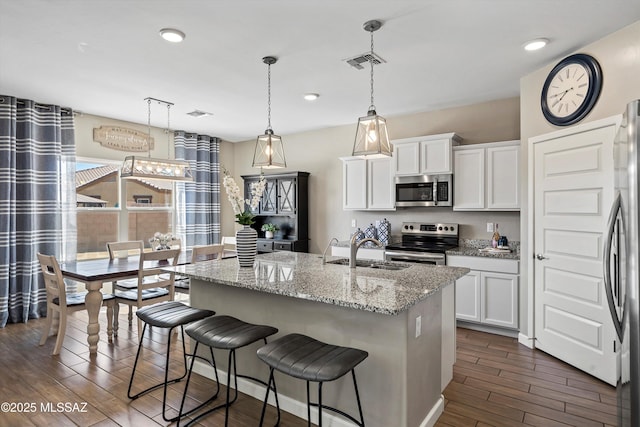 kitchen featuring visible vents, a sink, dark wood-type flooring, appliances with stainless steel finishes, and white cabinetry